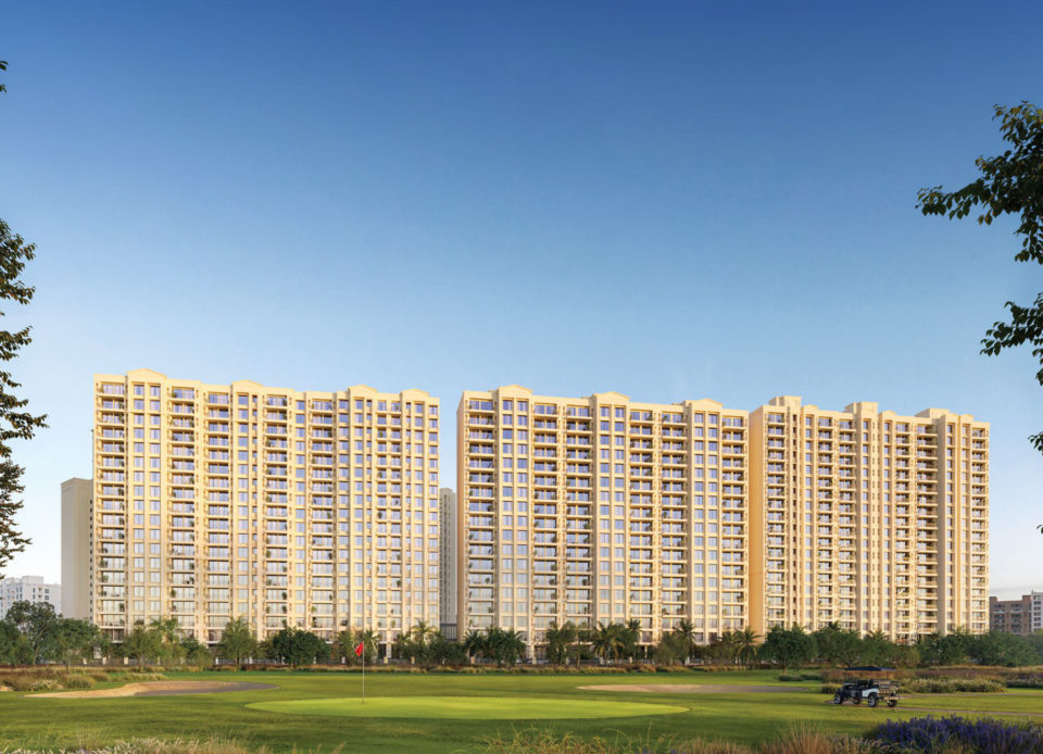 Three residential towers seen across a golf green under a blue sky