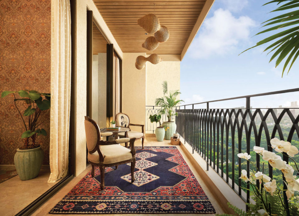 A deck with armchairs, a rug and an arched black railing overlooking greenery